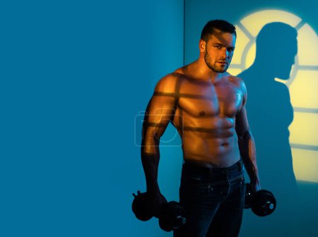 Foto de Musculoso sexy hombre con desnudo torso es posando con dumbbell - Imagen libre de derechos