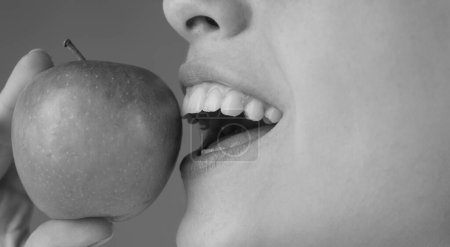 Téléchargez les photos : Belle jeune femme mangeant une pomme. Dents blanches saines ferment avec une pomme - en image libre de droit