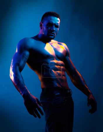 Foto de Modelo masculino sin camiseta en topless. Culturista desnudo en luz de neón azul - Imagen libre de derechos