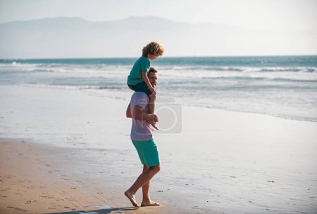 Photo for Father giving son ride on back outside. Dad and child enjoying outdoor. Little boy kid with daddy carrying him on shoulders - Royalty Free Image