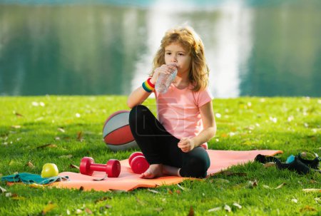 Photo for Sport kids boy. Kids relax on sport mat after sport exercises outdoor in park - Royalty Free Image