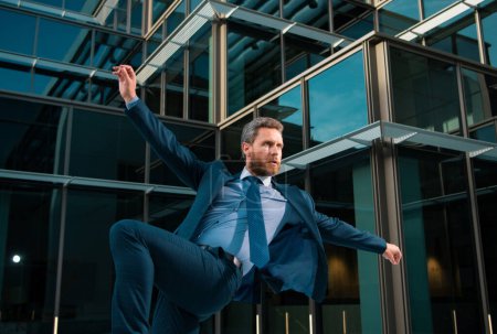 Téléchargez les photos : Homme d'affaires excité sautant à l'extérieur sur un immeuble de bureaux - en image libre de droit
