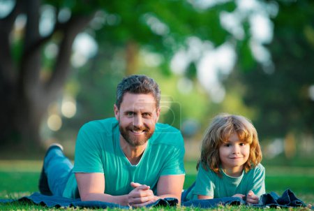 Téléchargez les photos : Père et fils se détendre sur l'herbe dans le parc - en image libre de droit