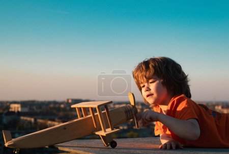 Foto de Niños jugando con aviones de madera vintage al aire libre. Retrato de niños sobre el fondo del cielo de verano. Concepto de viaje y libertad. Vacaciones de verano con niños - Imagen libre de derechos