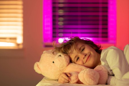 Photo for Child cannot sleep on bed at night in bedroom. Kid having sleeplessness. Kid boy sleeping in bed with night light - Royalty Free Image