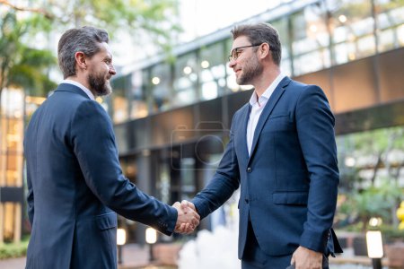 Photo for Handshake with business partner in the city for greeting. Handshake between two business men. Two businessmen shaking hands on city street. Business men in suit shaking hands outdoors. Business team - Royalty Free Image