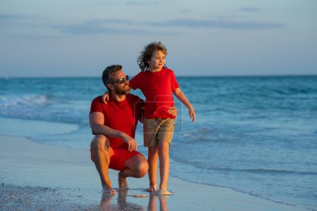 Foto de Padre e hijo abrazándose en la playa durante el día. Una familia amigable. Día de los Padres. Familia del amor, padre y un hijo caminan juntos en la naturaleza del mar en vacaciones de playa. Crianza, paternidad, amor de los padres - Imagen libre de derechos