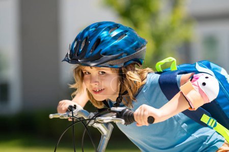 Foto de Un niño pequeño monta en bicicleta en el parque. Chico en bicicleta. Feliz niño sonriente en casco montando una bicicleta. El chico empieza a andar en bicicleta. Deportiva bicicleta de niño montar en bicicleta. bicicleta para niños - Imagen libre de derechos