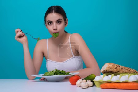 Photo for Vegetables diet. Funny woman eating healthy food, dieting. Girl eating vegetable diet salad in studio. Vegan salad. Female on diet. Dieting concept. Healthy lifestyle. Diet for weight loss - Royalty Free Image