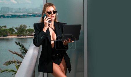 Photo for Full body of sexy secretary. Sexy business woman. Sexy business woman in a fashion suit. Elegant fashionable business woman wearing trendy clothes talking on phone using laptop. Business call - Royalty Free Image
