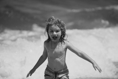 Foto de Emocionado niño jugando en la playa del mar - Imagen libre de derechos