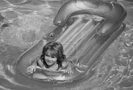 Téléchargez les photos : Vacances d'été. Enfant dans la piscine. L'été. Garçon souriant sur matelas gonflable en caoutchouc. - en image libre de droit