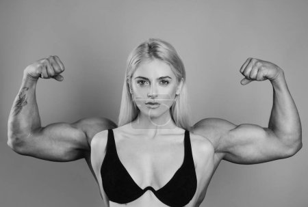 Photo for Female model keeps fit and healthy, raises hands and shows muscles, power. Strong muscle arms. Funny sport, woman with man muscle arms on back. Young girl showing bicep on her arm - Royalty Free Image