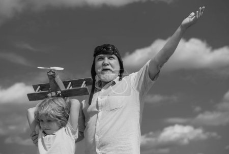 Téléchargez les photos : Grand-père et petit-fils avec avion sur fond bleu ciel et nuages. Hommes génération grand-père et petit-fils jouer à l'extérieur - en image libre de droit