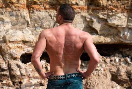 Photo for Handsome muscular young man from the back. Strong man with muscular body posing outdoors shirtless. Muscular bare torso - Royalty Free Image