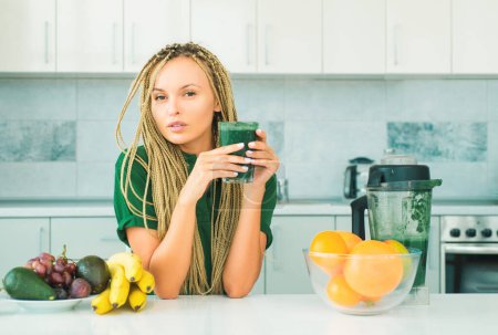 Photo for Making smoothie menu. Healthy eating alkaline diet. Healthy Green food. Weight loss. Healthy Lifestyle. Smiling young woman drinking green smoothie in kitchen - Royalty Free Image
