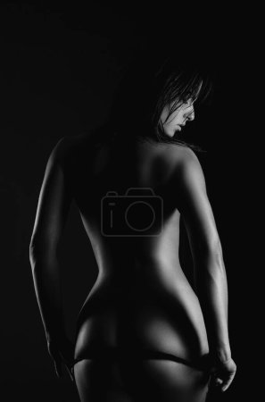 Foto de Sexy mujer nalgas con curvas perfectas. modelo de bikini se quita las bragas tanga posando sobre fondo negro, aislado - Imagen libre de derechos