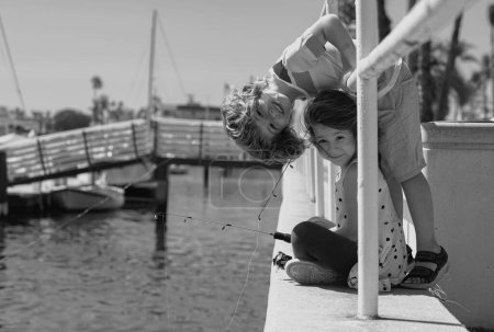 Téléchargez les photos : Kids fishing. Couple of children fishing on pier. Children at jetty with rod. Boy and girl with fish-rod - en image libre de droit