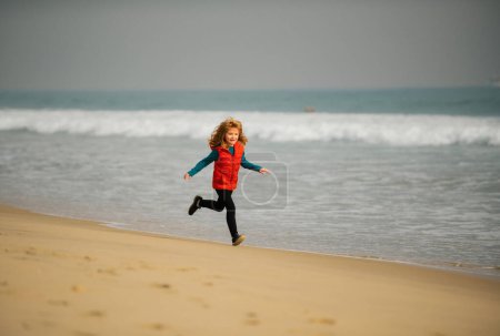 Photo for Sporty kid running in nature. Child running through water close to shore along the sea beach. Little runner exercising. Boy runs along the sea coast. Rest of children on summer vacation - Royalty Free Image