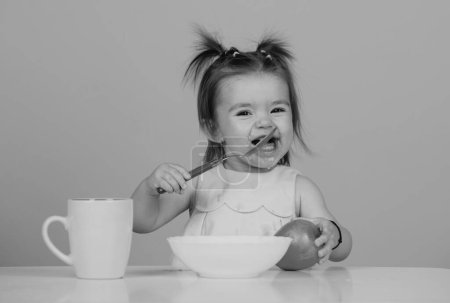 Photo for Baby child eating food. Happy smiling baby girl with spoon eats itself - Royalty Free Image