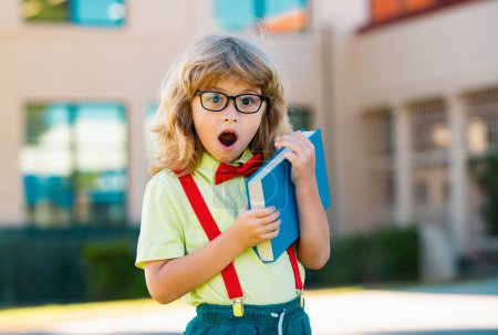 Photo for Smiling little student boy wearing school backpack and holding exercise book. Portrait of happy pupil outside the primary school. Closeup face of smiling hispanic schoolkid looking at camera - Royalty Free Image