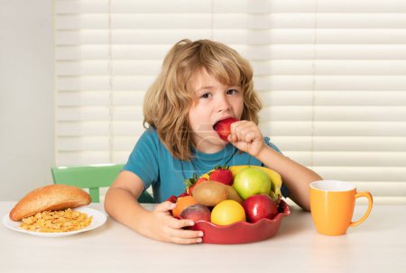 Photo for Child eats strawberry, organic fruits. Kid bot eating meal. Healthy nutrition for children. Child enjoy eating for breakfast or dinner with appetite. Hungry child eat tasty fruits and vegetables - Royalty Free Image