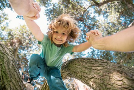 Téléchargez les photos : Père aidant son fils à grimper aux arbres. La main des pères. Protection de l'enfance. Mode de vie parental sain - en image libre de droit