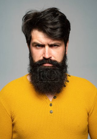 Foto de Retrato de hombre serio guapo con barba y bigote, se ve serio, aislado en la pared gris - Imagen libre de derechos