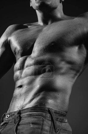 Téléchargez les photos : Muscle homme fort gars en jeans sur fond gris isolé. Corps coupe idéale - en image libre de droit