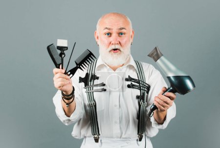 Téléchargez les photos : Coiffeur mature coiffeur dans le salon de coiffure. Vieux excité barbier étonné avec des outils d'équipement de coiffeur - en image libre de droit