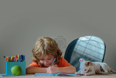 Téléchargez les photos : Enfant mignon avec un chiot étudie le chien et apprendre à la maison en classe - en image libre de droit