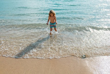 Téléchargez les photos : Un gamin qui saute dans les vagues. Saute par les éclaboussures de la mer. Vacances d'été pour enfants - en image libre de droit