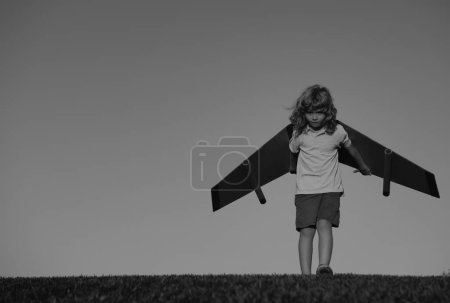 Foto de Un niño sueña con convertirse en piloto de cohetes. Concepto de imaginación y motivación. Niño feliz jugando con avión de juguete contra fondo azul cielo de verano - Imagen libre de derechos