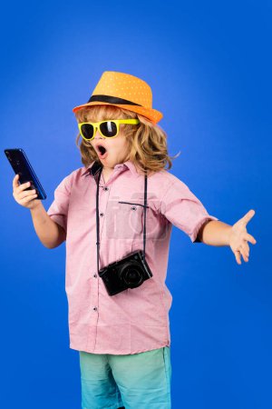 Photo for Kid traveller. Child travel with phone and camera. Child dreams of travel, adventure, vacation. Studio kids portrait - Royalty Free Image