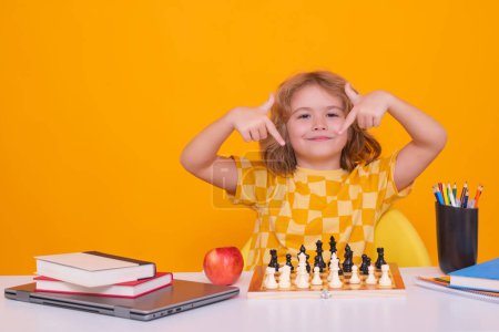 Photo for Clever child thinking about chess. Portrait of clever kid with chessboard. Boy play chess. Kid with chess on yellow isolated studio background - Royalty Free Image
