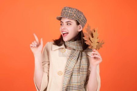 Photo for Autumn portrait woman with fall maple leaves on studio isolated background with copy space. Autumn portrait of cheerful woman with fall leaves wearing beret hat and autumn warm scarf - Royalty Free Image
