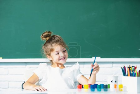 Photo for Funny school girl pupil drawing a picture. Cute little preschooler child drawing at school - Royalty Free Image
