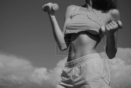 Foto de Cintura delgada. Mujer haciendo ejercicio con pesas sobre el fondo del cielo. Cintura de fitness. Abdominales fuertes mostrando - Imagen libre de derechos