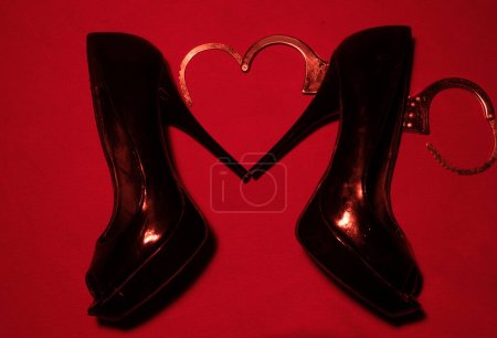 Foto de BDSM, concepto de comportamiento sexual. Zapato rojo de tacón alto con esposas - Imagen libre de derechos