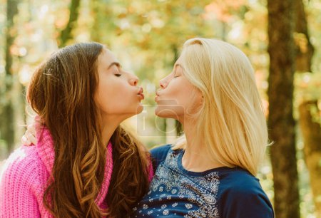 Photo for Friendly kiss. Girls friends kissing. Girlish friendship concept. Blonde and brunette walking in autumn park defocused background. Women kiss cute faces close up. Kiss me. Best friends forever. - Royalty Free Image