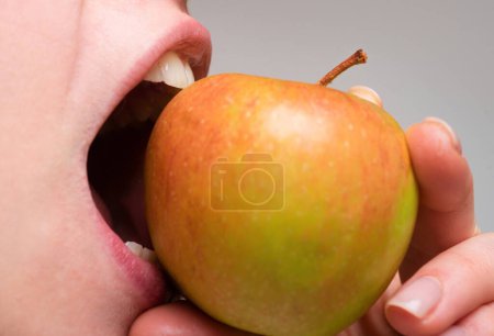 Téléchargez les photos : Femme heureuse en bonne santé mangeant des pommes macro proche. Mordre une pomme. Bouche fermée. Soins dentaires - en image libre de droit