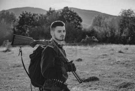 Photo for Hunter man. Hunter with a backpack and a hunting gun. Hunting period, autumn season. Male with a gun. A hunter with a hunting gun and hunting form to hunt - Royalty Free Image