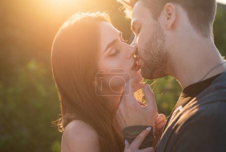 Téléchargez les photos : Un homme avec des baisers de femme. Gros plan portrait d'un beau jeune couple attendant de s'embrasser contre la lumière du coucher du soleil - en image libre de droit
