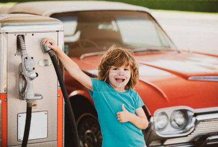 Téléchargez les photos : Ravitailler la voiture. Station essence. Enfant contre automobile rétro rouge - en image libre de droit