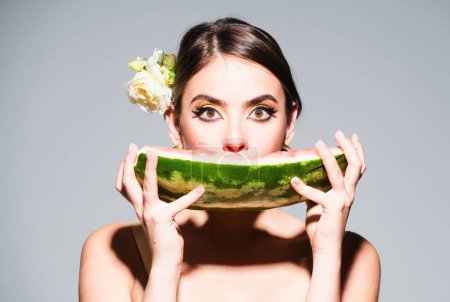 Téléchargez les photos : Gros portrait de jeune femme hispanique ou italienne sensuelle mangeant de la pastèque isolée sur fond gris - en image libre de droit