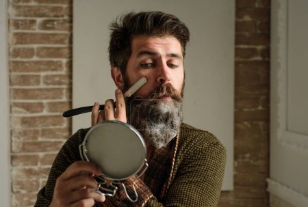 Foto de El hombre barbudo - el estilo casero de la barba. Retrato de barba de hombre con estilo. Navaja de afeitar peluquero, barbería. Peluquería vintage, afeitado. Retrato del hombre afeitado - Imagen libre de derechos
