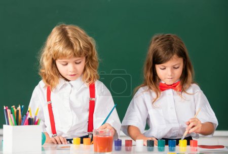 Téléchargez les photos : Kids pupils learning painting. Portrait school kids doing art homework. Children drawing on elementary school - en image libre de droit