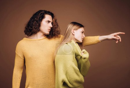 Foto de Portret de elegantes modelos masculinos y femeninos confiados con peinado de la naturaleza con un suéter amarillo y verde y de pie juntos mirando cautivadoramente a la cámara - Imagen libre de derechos