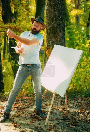 Photo for Autumn outdoor portrait of artist - He painting autumn picture. Man artist painting autumn picture - Royalty Free Image