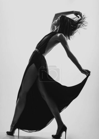Foto de Elegante jovencita caliente bailando. Movimiento. Mujer en vestido negro - Imagen libre de derechos